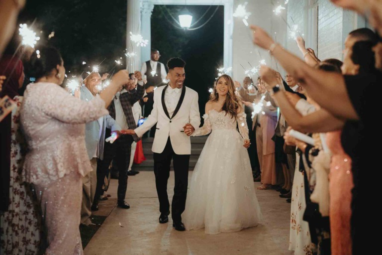 Couple exits wedding amidst sparklers.